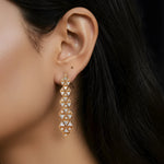 Close-up of an ear wearing a geometric gold earring with dark hair and skin background