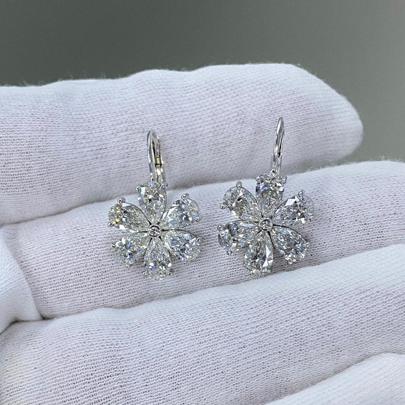 Pair of silver flower-shaped earrings on a white jewelry display.