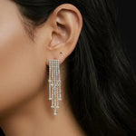 Close-up of a person wearing a dangling earring with a dark background